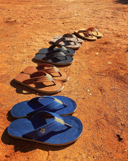 Five pair of cork sandal of different colors in a row on sand showing style and comfort