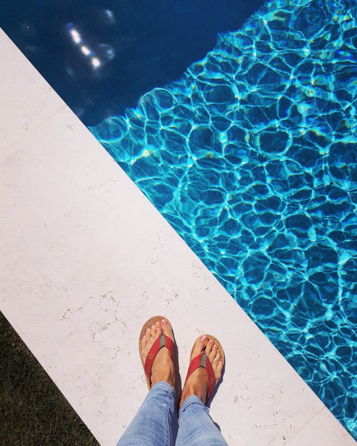 feet wearing red cork sandals by the pool